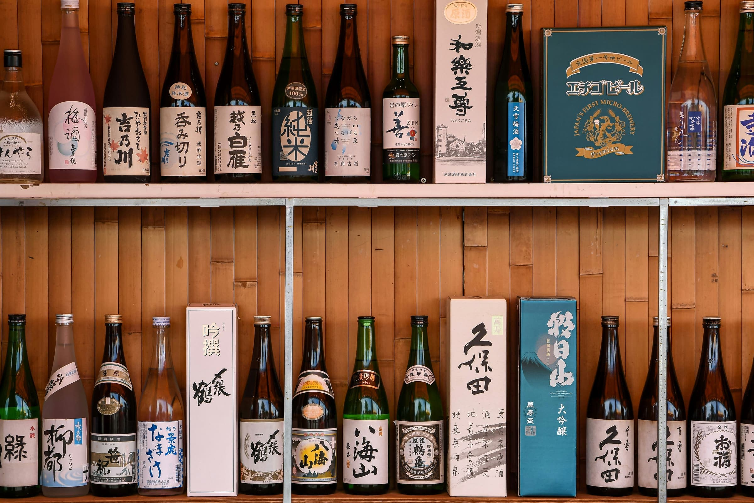 木の壁に取り付けられた二段の棚。一升瓶と四合瓶、化粧箱がすきまなく並んでいる。